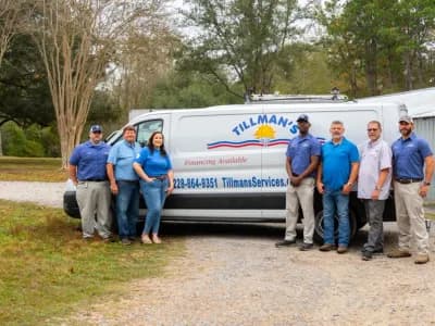 Team of Tillman's heating service professionals standing next to branded service van in Gulfport, MS, showcasing expertise in heating solutions and customer service.
