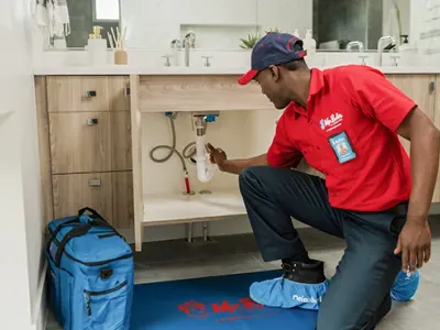 Mr. Rooter Plumbing technician working underneath a sink.