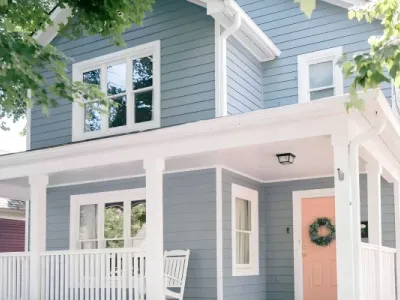 Blue siding, white trim, and a pink door define a home painted by Paint‑Pro’s.