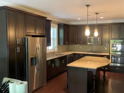 Dark cabinetry contrasts stainless appliances in a modern kitchen styled by Paint‑Pro’s.