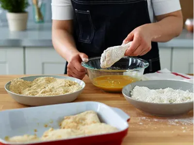Preparing hand breaded chicken in flour and egg wash