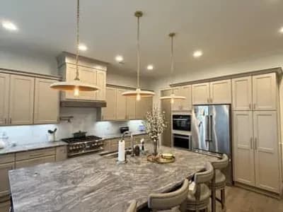 Luxury open kitchen and dining area with greige wainscoting, stone island, and brass chandelier pendants painted by OVO Painting in Atlanta