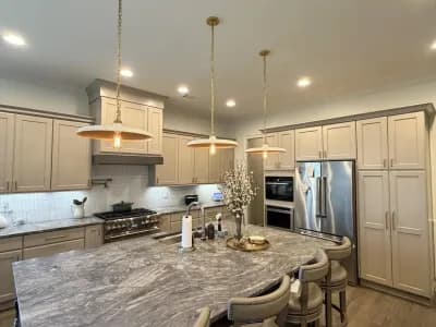 Luxury open kitchen and dining area with greige wainscoting, stone island, and brass chandelier pendants painted by OVO Painting in Atlanta