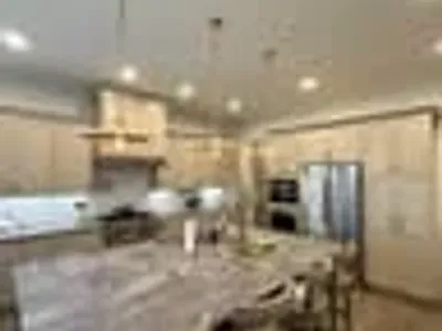 Luxury open kitchen and dining area with greige wainscoting, stone island, and brass chandelier pendants painted by OVO Painting in Atlanta