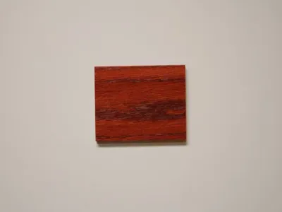 Red oak wood sample with a vibrant wild cherry stain, emphasizing the striking grain patterns and rich color depth, representative of C&S Cabinets' selection for luxurious custom cabinetry finishes.