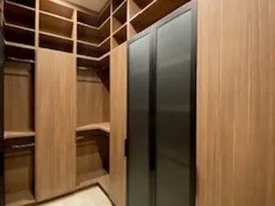 Modern walk-in closet with wooden shelves and frosted glass doors.
