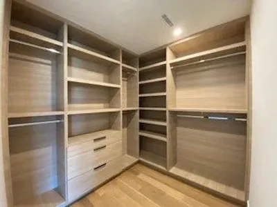 Spacious walk-in closet with light wood shelves and drawers.