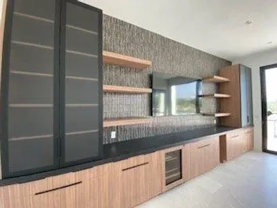 Modern kitchen with wooden cabinets, black countertops, and open shelves.