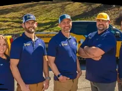 Malone Painting team standing in front of company trucks, smiling and wearing branded polo shirts