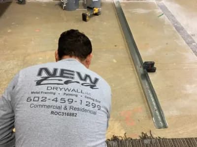 Phoenix Licensed and Bonded Drywall Installer wearing a New Era Drywall Company shirt prepares a floor for metal framing installation