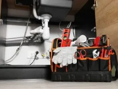 Plumber's tool bag on floor under kitchen sink