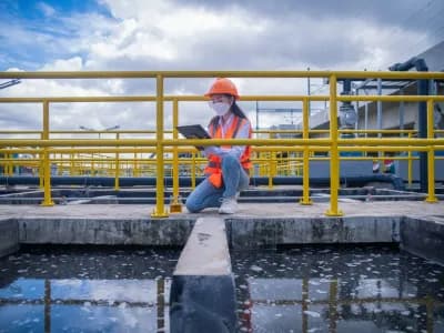 Worker take water from the wastewater treatment pond to check the quality of the water. After going through the wastewater treatment process,she wearing face mask to protect pollution.