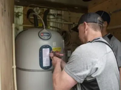 Petersen Plumbing employees work on a water heater.