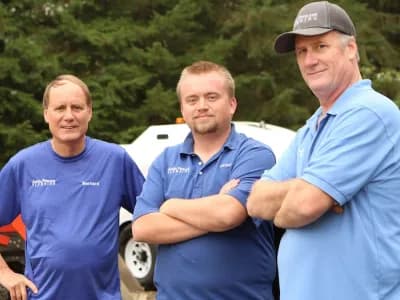 Three Petersens standing in front of plumbing equipment.