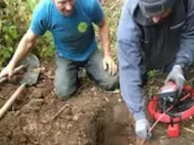 Several men digging a hole thru tree roots.