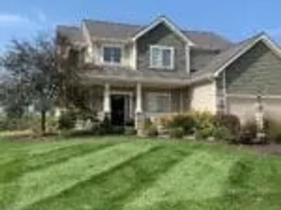 Freshly mowed and mulched Fort Wayne lawn with landscaped shrubs in front of suburban home.