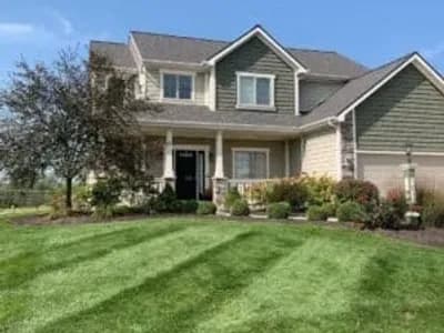 Freshly mowed and mulched Fort Wayne lawn with landscaped shrubs in front of suburban home.